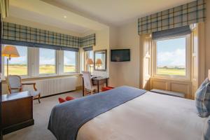 a bedroom with a bed and a desk and windows at Royal Golf Hotel in Dornoch