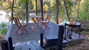 a wooden dock with two chairs and a table at Divas Upes in Koknese