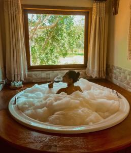 a woman is sitting in a cloud bathtub with a window at Pousada Chalé Amoreira in Visconde De Maua