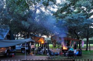 Sondela Nature Reserve & Spa Makhato Lodges في بيلا بيلا: مجموعة من الناس يجلسون حول النار في الحديقة