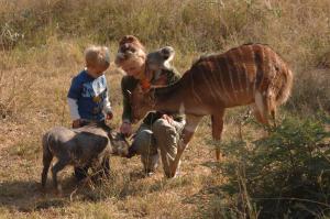 a woman and a child and animals and a giraffe at Sondela Nature Reserve & Spa Makhato Lodges in Bela-Bela