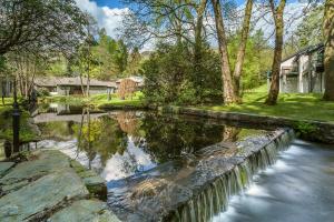 a river with trees and a house in the background at Langdale Hotel & Spa in Ambleside