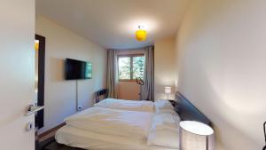 a bedroom with a bed with white sheets and a window at Chesa Seraina Abitaziun Seraina 3 - Cream - Madulain in Madulain