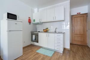 a white kitchen with a sink and a refrigerator at Enchanting Unique Flat - Ace Location in Porto