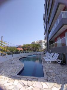 uma piscina com cadeiras e um edifício em terraços do maitinga em Bertioga