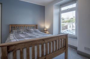 ein Schlafzimmer mit einem Holzbett und einem Fenster in der Unterkunft Cambrian Cottage - 3 Bedroom Cottage - Tenby in Tenby