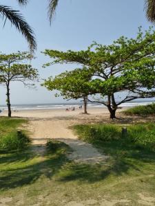 a sandy beach with trees and people on the beach at terraços do maitinga in Bertioga