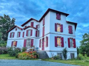 Une grande maison blanche avec volets rouges dans l'établissement Domaine Abartiague, à Ossès