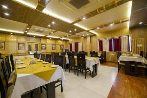 a restaurant with tables and chairs in a room at Hotel Karan Vilas in Agra