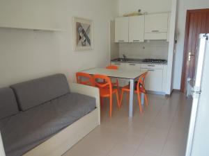 uma sala de estar com um sofá, uma mesa e cadeiras em Residence Itaca em Bibione