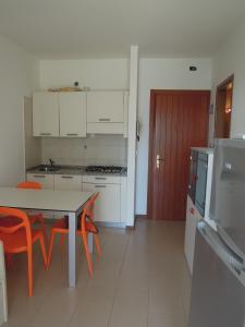 uma cozinha com uma mesa e cadeiras e um frigorífico em Residence Itaca em Bibione