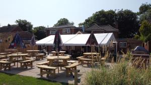 eine Gruppe von Picknicktischen und Sonnenschirmen auf einer Terrasse in der Unterkunft The White Hart in Ashill