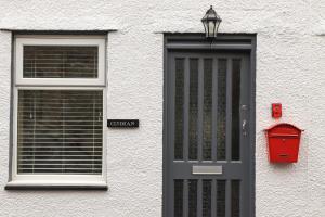 a white building with a black door and a mailbox at Clydfan in Caernarfon