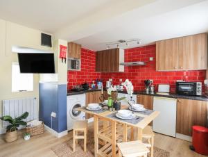 a kitchen with a table and a red brick wall at Clydfan in Caernarfon