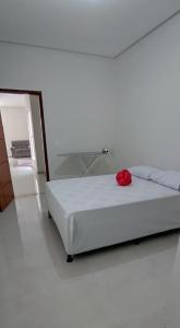ein weißes Zimmer mit einem Bett mit einer roten Rose darauf in der Unterkunft Casa do Lamarques in Piranhas