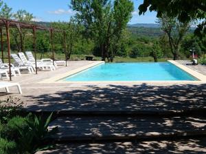 una gran piscina con sillas blancas y árboles en Les Maisons De Chante Oiseau, en Sigonce