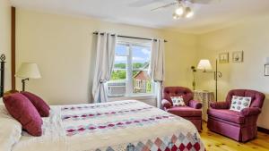 a bedroom with a bed and two chairs and a window at Bayview Pines Country Inn B&B in Mahone Bay