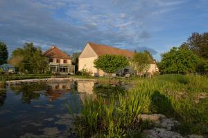 une maison avec un étang en face de celle-ci dans l'établissement Gîte LA MELINOTHE - 12 personnes - Grand gîte de charme indépendant 5 étoiles, à Paisy-Cosdon