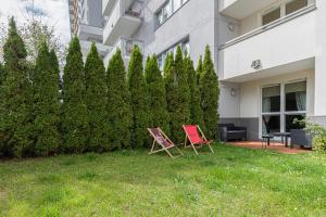 two chairs sitting in the grass in front of a building at Apartment Trzy Żagle Gdańsk by Renters in Gdańsk