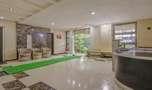 ムンバイにあるTreebo Trend Welcome Apartmentsのロビーには椅子と緑の敷物を用意したバーがあります。