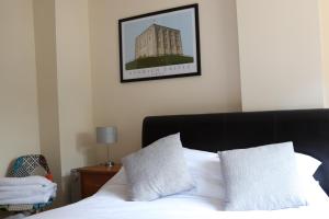 a bed with white sheets and a picture of a building at The White Hart in Ashill