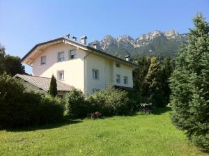 a house in a field with mountains in the background at Villa Ducati in Vattaro