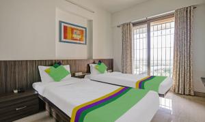 dwa łóżka w pokoju z oknem w obiekcie Treebo Trend Welcome Apartments w Bombaju