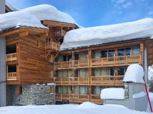 Cabaña de madera grande con nieve en el techo en Hôtel Ski Lodge - Village Montana en Val dʼIsère