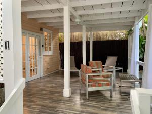 un porche cubierto con 2 sillas y una mesa en Douglas House en Key West