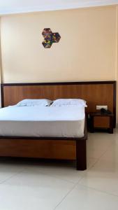 a bed with a wooden headboard in a room at Hotel Meridian Palace in Kannur