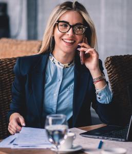 een vrouw die aan een tafel zit te praten op een mobiele telefoon bij Plaza Hotel Plovdiv in Plovdiv