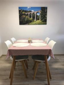 une table avec des chaises blanches et un tissu de table rouge et blanc dans l'établissement Apartmán Jedlička, à Telgárt