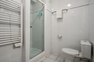 a white bathroom with a shower and a toilet at Appart'City Classic Nîmes in Nîmes