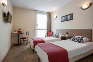 a hotel room with two beds and a table at Appart'City Classic Nîmes in Nîmes