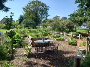 a table and chairs in a garden with a fence at Gut Huthmacherhof in Jülich