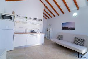una cocina con armarios blancos y un sofá en una habitación en Apartamentos Anjomacar II en Teguise