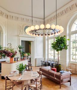 uma grande sala com mesas e cadeiras e um lustre em Maison du Val - Les Maisons de Campagne em Saint-Germain-en-Laye