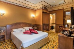 una camera da letto con un letto con cuscini rossi di River Palace Hotel a Roma