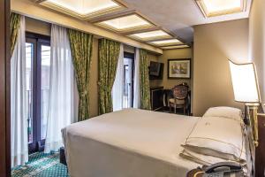 una camera da letto con un grande letto bianco e una finestra di River Palace Hotel a Roma