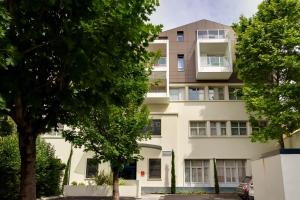 un immeuble d'appartements avec des arbres devant lui dans l'établissement Privilège Appart Hôtel Saint Exupéry, à Toulouse