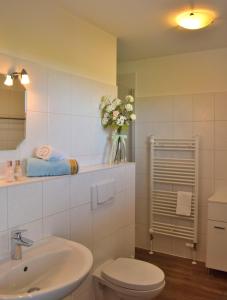 a bathroom with a toilet and a sink and a vase of flowers at Fehmarnstrand 77 Whg 5 in Staberdorf