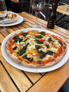 uma pizza num prato branco numa mesa de madeira em Haus zur Eiche Private 1 Zimmerstudios em Chur