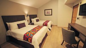 a hotel room with two beds and a television at Hotel Flamingo Inn in Querétaro