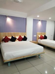 a bedroom with two beds with red and black pillows at The White Orchid Luxury Service Apartments in Ernakulam
