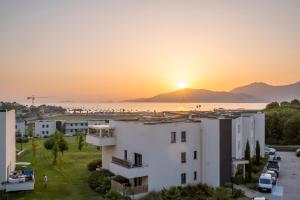 una vista de un edificio con la puesta de sol en el fondo en Superbe T2 climatisé, proche plage - belle vue mer, en Porticcio