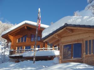 Cabaña de madera con nieve en el techo en Les Gîtes du Cairn, en Vernamiège