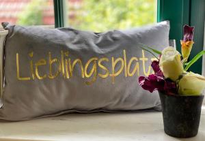 a pillow with the word leominster next to a vase of flowers at Haus Grüne Idylle in Bannewitz