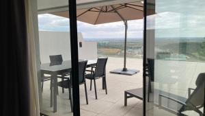 a table and chairs with an umbrella on a balcony at Verdi Santarém in Santarém