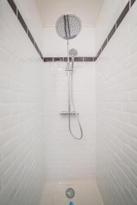 een douche in een wit betegelde badkamer bij VOLTAIRE #2 - Studio - 1 chambre in Brive-la-Gaillarde