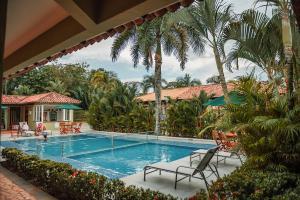 una piscina con sillas y palmeras en Hotel Paloverde Villas Campestres, en Villavicencio